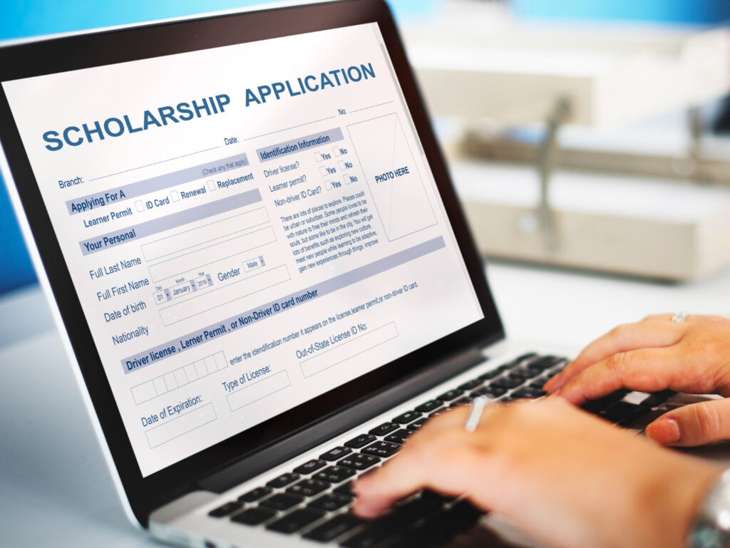 person filling scholarship form in his laptop sitting on a table
