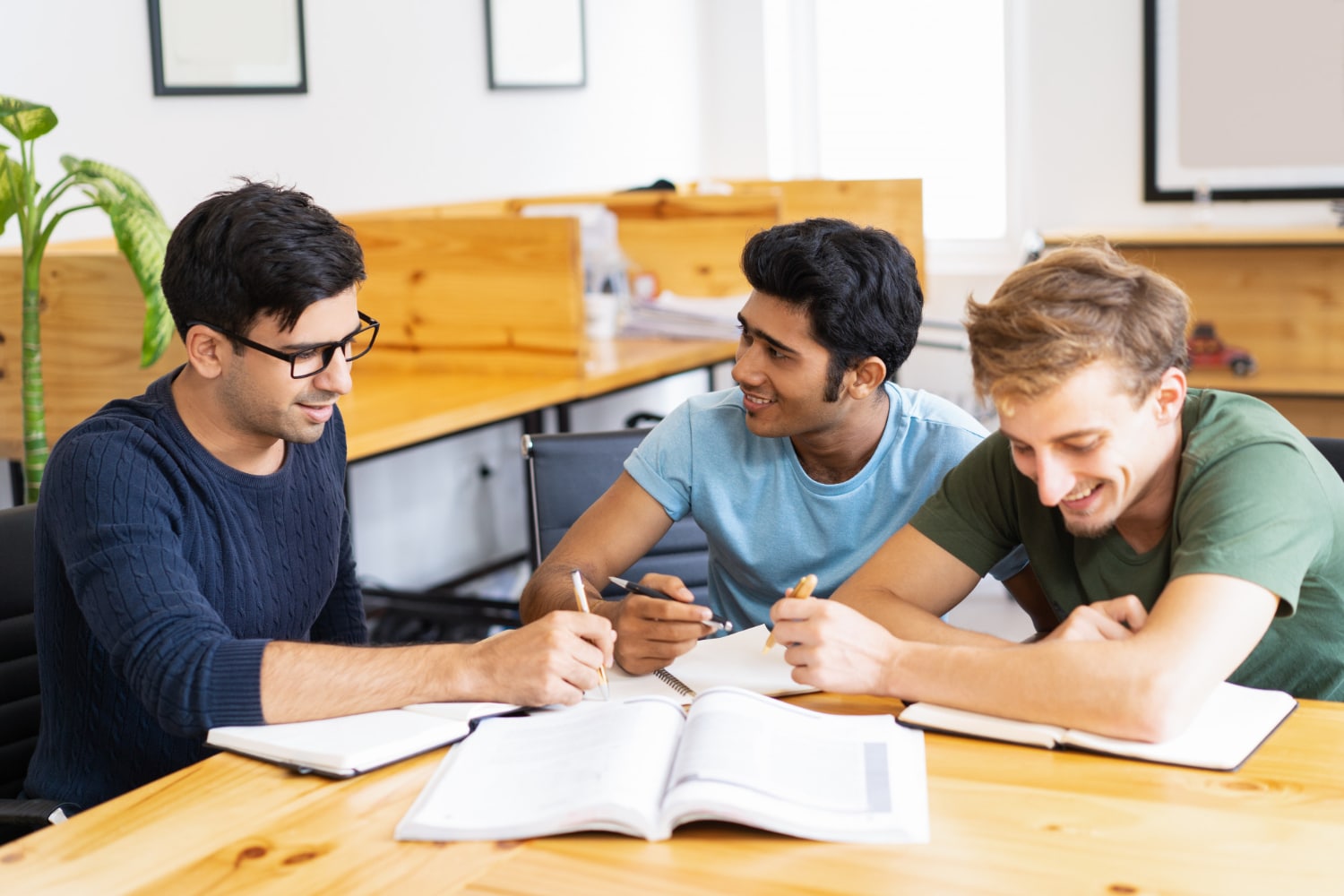 three friends sitting together with some notebooks on table