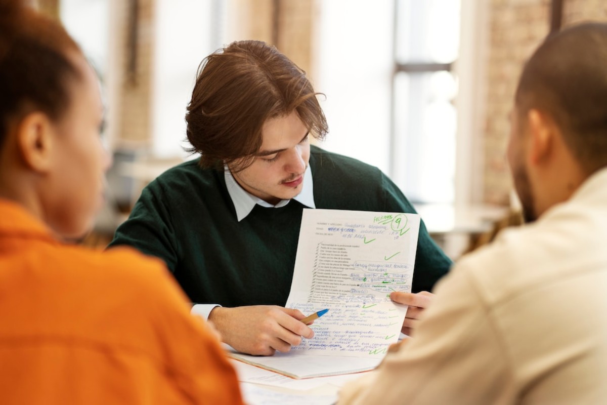 A group discussion around a detailed document with notes and corrections, highlighting collaboration and feedback in a study environment.