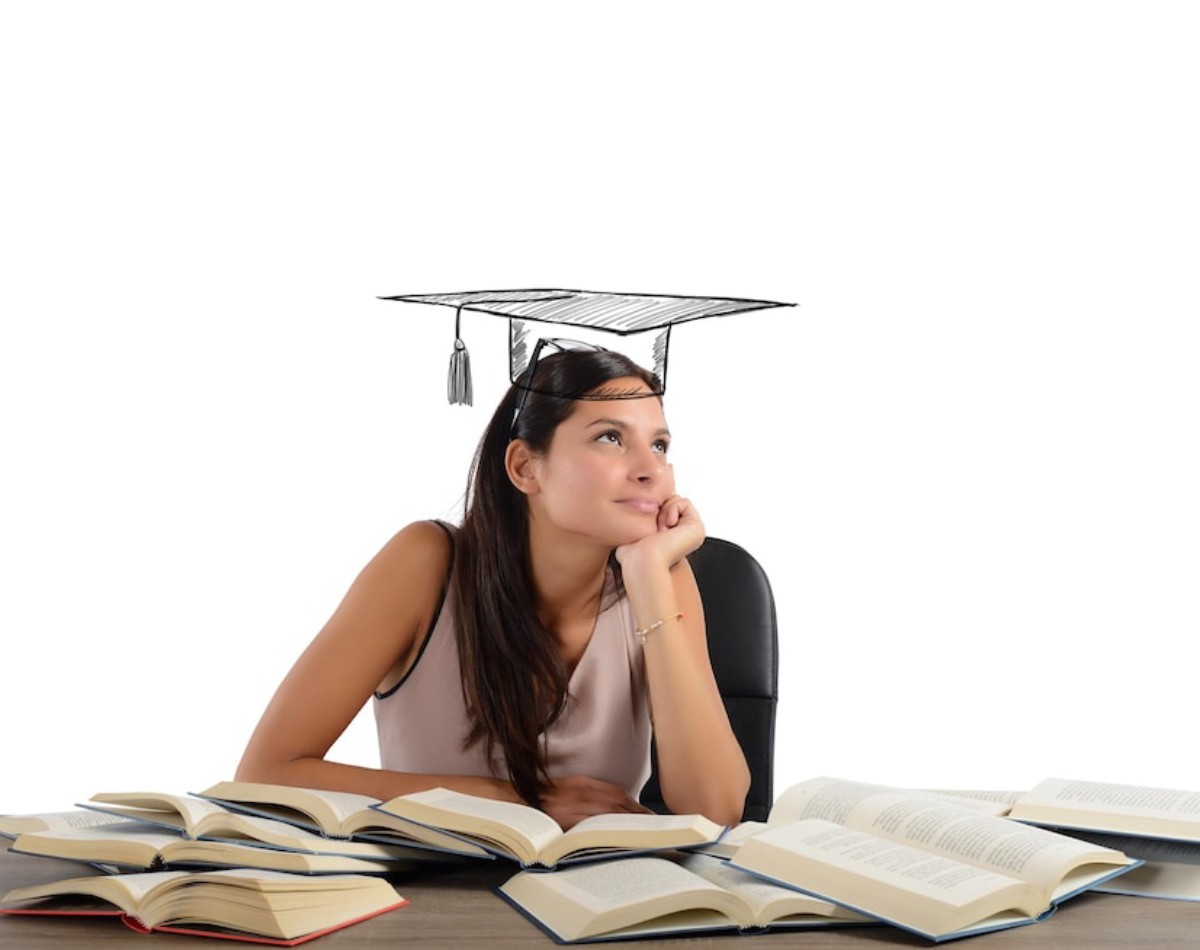 A woman rests her chin on her hand, surrounded by open books, with a graduation cap drawn above her head, symbolizing academic achievement.